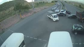 CCTV frame at 1:25 — a white utility truck crossing the intersection ahead of a dark red dump truck.